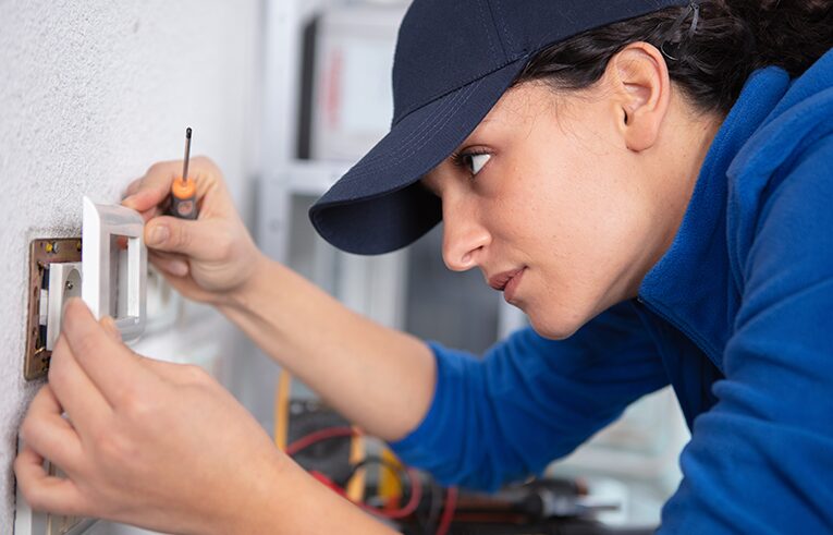 Électricienne atelec à Bordeaux installant un interrupteur mural avec précision