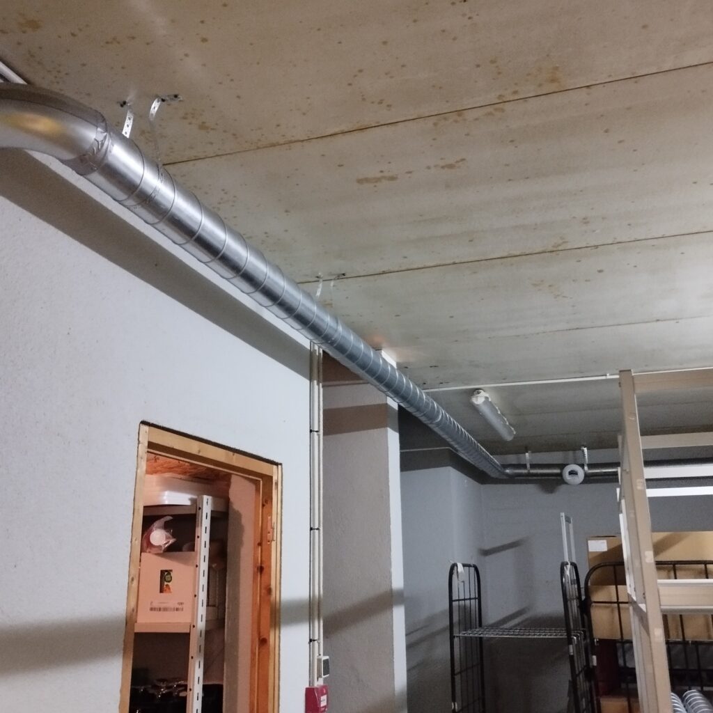 Conduit métallique au plafond dans local technique rénové par atelec à Bordeaux, sous-sol de stockage fonctionnel