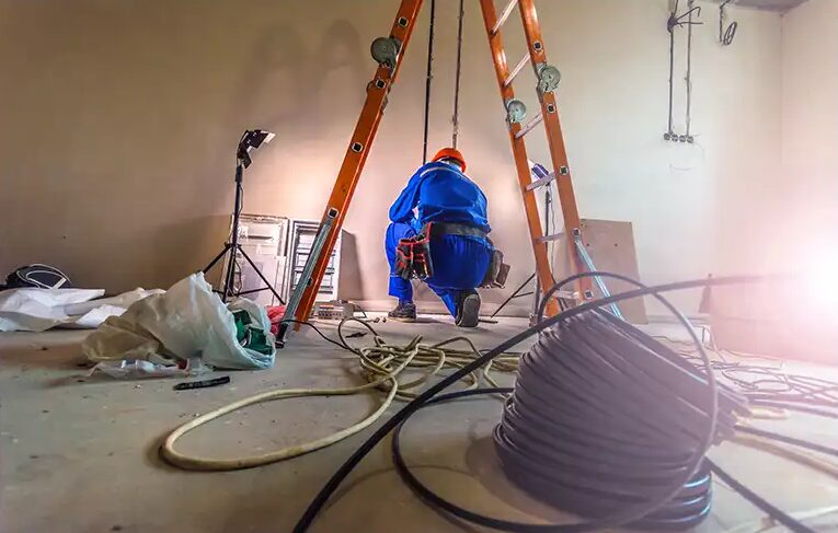 Ouvrier atelec sur chantier de rénovation électrique avec câbles et outils au sol à Bordeaux