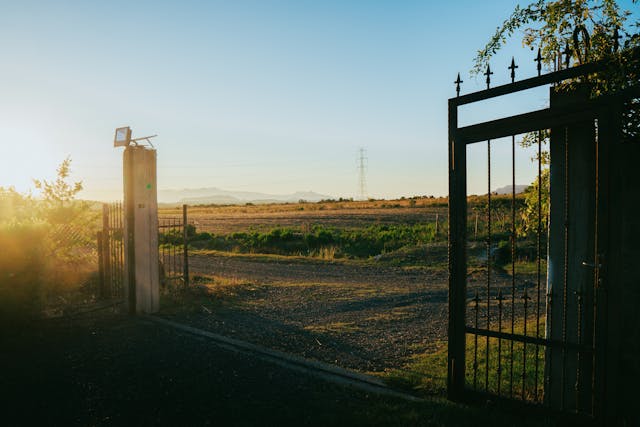 Portail métallique ouvert sur champ au coucher du soleil, installation atelec en campagne près de Bordeaux